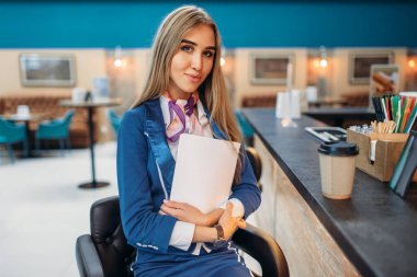 Hostes barda oturur Havaalanı Cafe counter. Hostes alanında kalkış, uçuş görevlisi bekleyen bölgedeki kahve içer