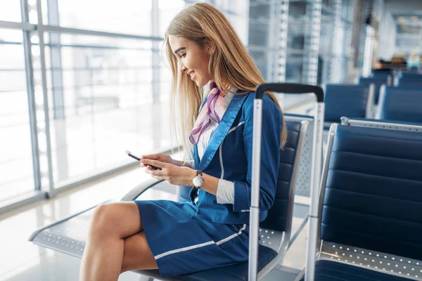 Azafata Con Maleta Sentada Asiento Sala Espera Aeropuerto Usando Teléfono —  Fotos de Stock