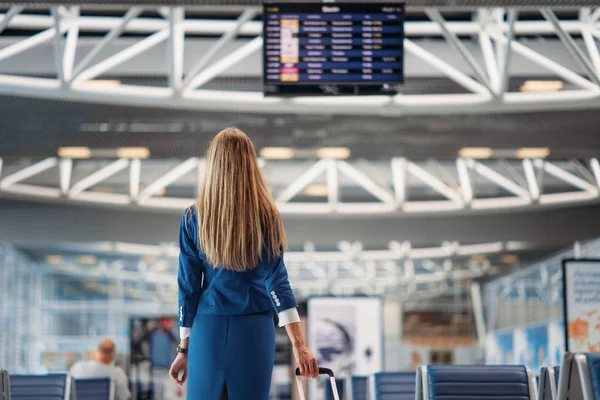 スーツケースと制服を着たセクシーなスチュワーデスは ビュー空港 バックでスコアボードに見えます 手荷物 Aviatransportations ジョブ ターミナル 乗務員の荷物を空気のホステス — ストック写真