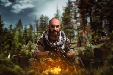 Ormanda saklanıyor elinde silahla acımasız terörist üniformalı. Terörizm ve terör, kamuflaj asker