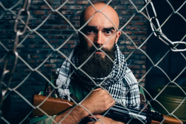 金属グリッド Mojahed に対して均一にひげを生やしたテロリスト テロとテロ カーキ色の迷彩 背景にレンガの壁の兵士 — ストック写真