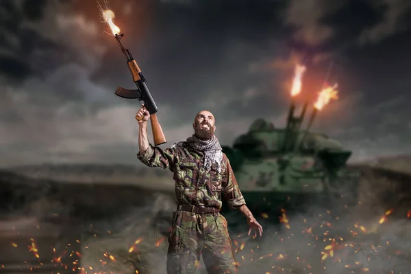ひげを生やしたテロリストの手にライフルでは 爆発と火災で立っています テロとテロ カーキ色の迷彩の兵士 — ストック写真