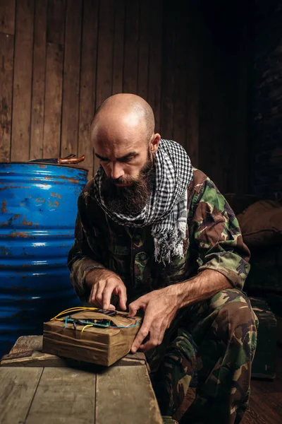 Mojahed 制服でひげを生やしたテロリスト テロとテロ カーキ色の迷彩の兵士燃料または化学薬品の背景に弾薬箱のバレル — ストック写真