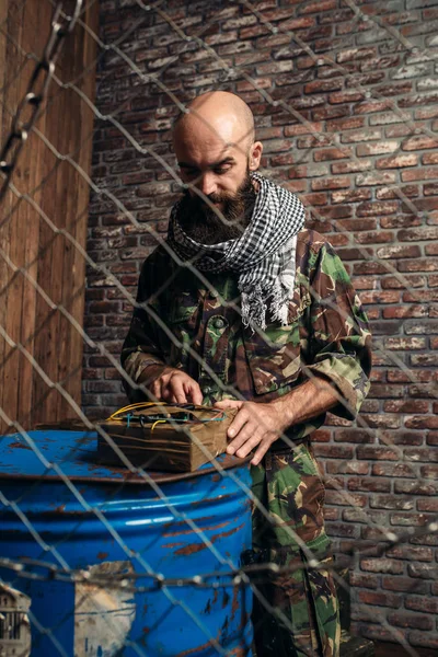 制服を着たひげを生やしたテロリストは 燃料や化学物質 爆発で男性 Mojahed のバレルに爆弾を設定します テロとテロ カーキ色の迷彩の兵士 — ストック写真