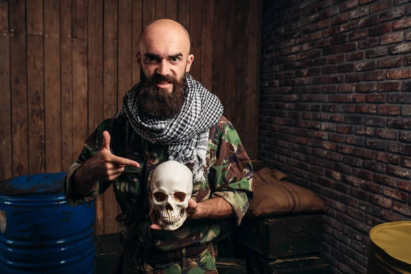 身着制服的恐怖分子手里拿着人的头骨 Mojahed 恐怖和恐怖 胡子的士兵在卡其色伪装 桶燃料或化学品的背景 — 图库照片