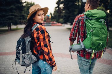 Hikers with backpacks traveling in tourist town. Summer hiking. Hike adventure of young man and woman clipart