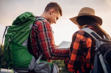 Yürüyüşçüler sırt çantaları ile haritada, gezi turist kasabasında görünüyor. Hiking yaz. Macera genç erkek ve kadın zammı