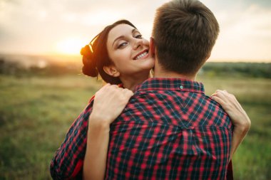 Çift hugs birlikte çayır on gün batımında seviyorum. Erkek ve kadın, piknik alanında romantik basın gösterimi