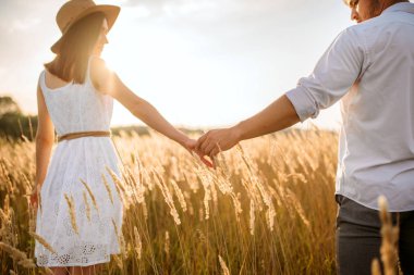 Aşk çift çavdar alanına sunset Bulvarında yürürken ellerini tutun. Yaz çayır, mutlu ilişkiler üzerinde şirin aile