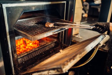 Şef el eldiven bir biftek ızgara fırın hazırlanıyor. Taze biftek yemek, Mutfak gıda hazırlama