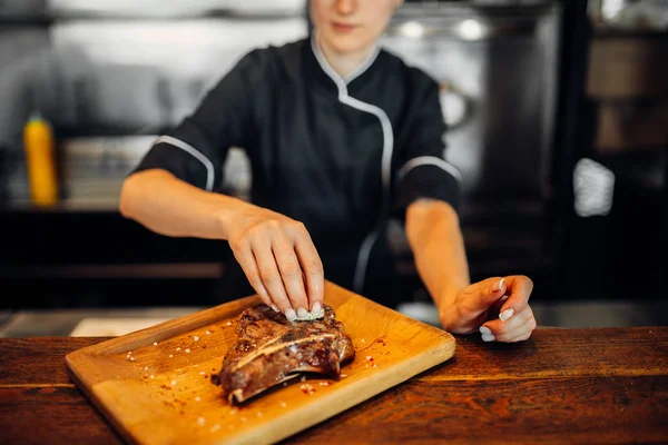 女性調理準備新鮮な調味料を振りかけるステーキ 焼き肉 ステーキ料理 キッチンで食事の準備 — ストック写真