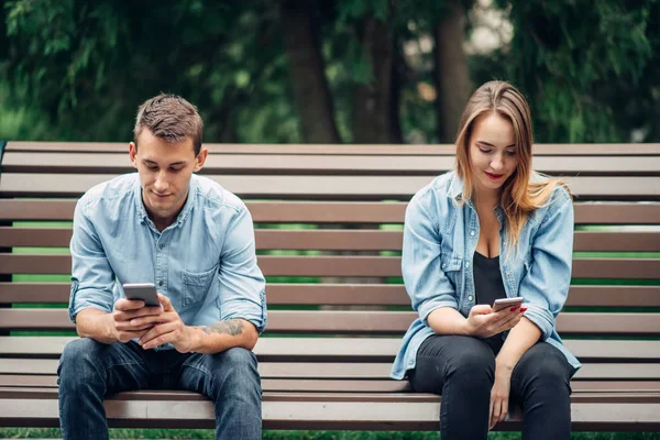 在公园的长凳上 电话成瘾夫妇 男人和女人使用他们的智能手机 — 图库照片