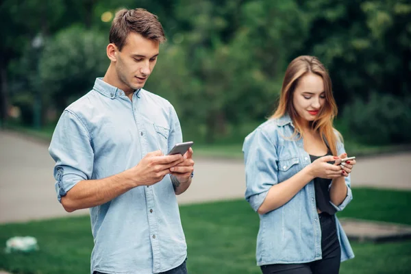 电话成瘾的人 在夏季公园的情侣 男人和女人使用他们的智能手机 — 图库照片