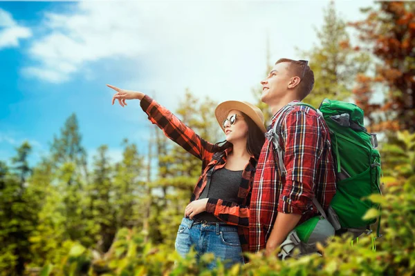 两个带着背包旅行的游客穿过树林 在夏日森林里徒步旅行 年轻人和女人远足冒险 — 图库照片
