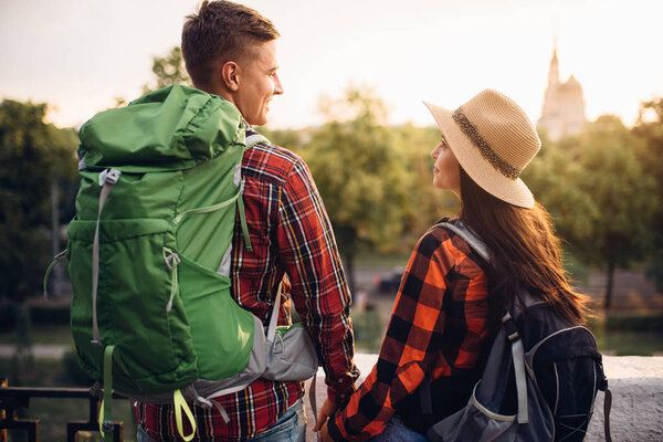 Hikers with backpacks go sightseeing in tourist town on vacation. Summer hiking. Hike adventure of young man and woman