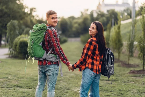 爱两个游客带着背包牵手 快乐的度假 青年男女夏季探险 在城市公园漫步 — 图库照片