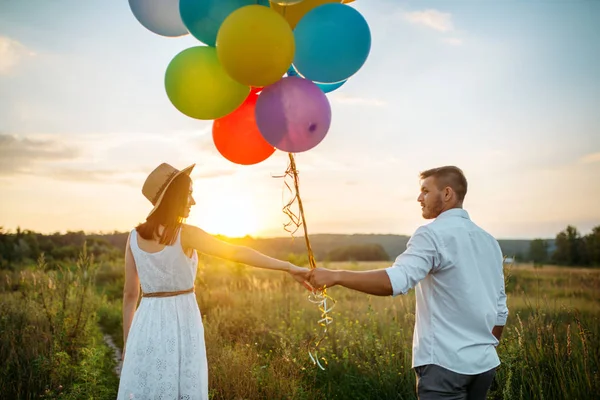 快乐的情侣在麦田里捧着一束气球和亲吻 美丽的夫妇休闲在夏天草甸 — 图库照片