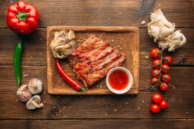 Sulu ızgara kaburga ve ahşap masa, üstten görünüm üzerinde et parçası. Biber, sarımsak ve arka plan üzerinde bitki