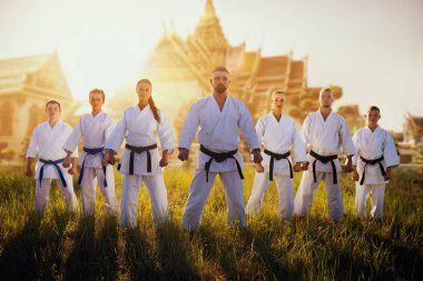 Günbatımı üzerinde Antik tapınak karşı kimono erkek ve dişi karate grubu. Savaş sanatı eğitim açık. Arka plan ile fotoğraf düzenleme
