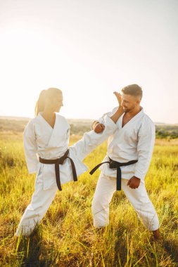 Kadın karate erkek eğitmen ile eğitim germe egzersiz yapmak. Savaş sanatı egzersiz açık, teknik uygulama, kendini savunma