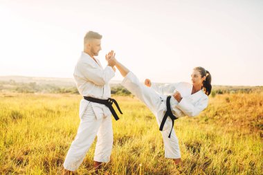 Kadın karate erkek eğitmen ile eğitim germe egzersiz yapmak. Savaş sanatı egzersiz açık, teknik uygulama, kendini savunma