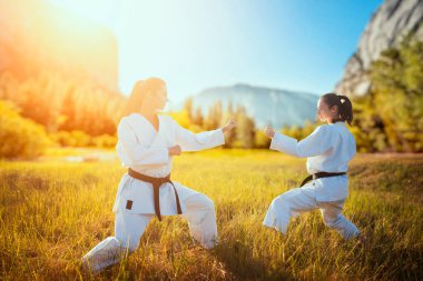 Kimono eğitim mücadele beceri yaz alanında iki kadın karate. Savaş sanatı egzersiz açık, teknik uygulama, arka plan ile fotoğraf düzenleme