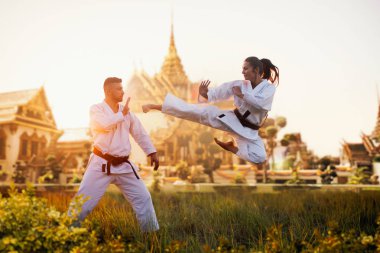 Kadın karate savaşçı trenler uçuş antik tapınak karşı ana, eğitim ile tekme. Savaş sanatı savaşçıları egzersiz açık, tekniği uygulaması. Arka plan ile fotoğraf düzenleme