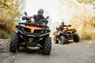 Kask içinde iki quad bisiklet bisikletçi ormanda, önden görünüm yayılıyor. ATV üzerinde aşırı spor sürme ve seyahat, quadbike macera