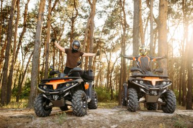 İki atv bisikletçi kask içinde mutlu bir şekilde ellerini yukarı aşırı offroad yerden önden görünüm binme, sonra Kaldır. Serbest sürüşte quad bisiklet, quadbike yaz macera