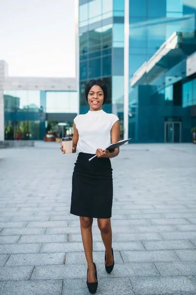 段ボールのコーヒー カップとメモ帳屋外 背景にオフィスビルとビジネスの女性 スカートと白のブラウスに黒の実業家 — ストック写真