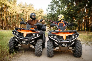 Kask içinde iki atv bisikletçi tehlikeli aşırı offroad binme, önden görünüm, yaz orman arka plan üzerinde önce iyi şans için yumruk vurur. Serbest sürüşte quad bisiklet, quadbike macera