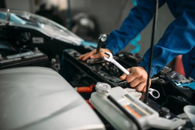 Erkek teknisyen araba motoru ile çalışır. Otomatik-servis, araç bakım, tamirci araçları ile