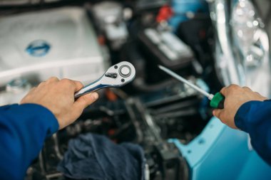 Tornavida ve anahtarı ile erkek teknisyen el, araba ile arka plan üzerinde başlık açıldı. Auto-servis, araç bakım
