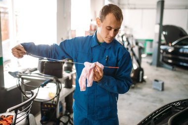 Erkek teknisyen araba motor yağ seviyesi yağ çubuğu ile denetler. Otomatik-servis, araç bakım, tamirci araçları ile