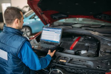 Mühendis dizüstü bilgisayar ile auto-hizmetinde bilgisayar teşhis arabanın motoru yapar. Araç kablolama muayene