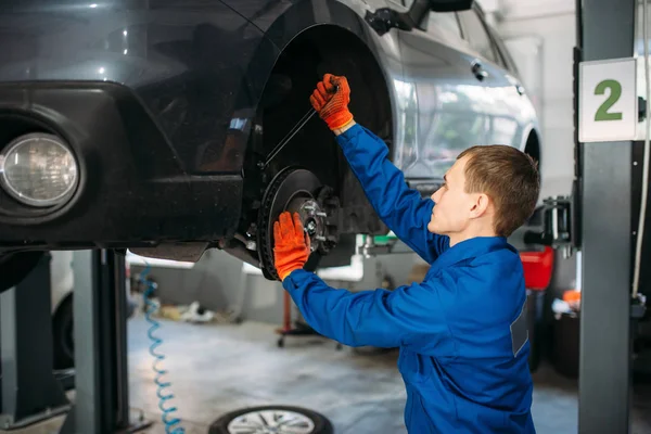 Mechanic with a wrench repairs the suspension of the car. Tire service, vehicle maintenance