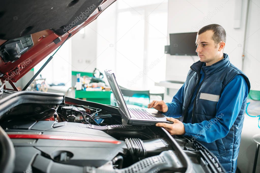 Engineer makes computer diagnostics of the car in autoservice. Vehicle wiring inspection