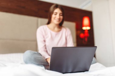 Gülümseyen yatak ve uses laptop, Günaydın, yatak odası interoir arka plan üzerinde oturan kadın