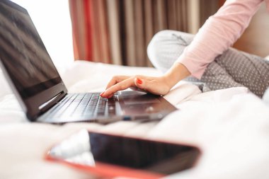 Kadın pijama bizzat kahve içer ve yatak, Günaydın, yatak odası interoir dizüstü bilgisayar arka plan üzerinde kullanır