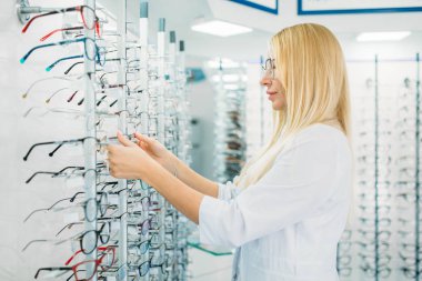 Kadın optometrist gözlük optik mağazada gösterir. Gözlük seçim profesyonel gözlükçü ile bakmak