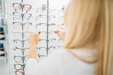 Kadın optometrist gözlük optik mağazada gösterir. Gözlük seçimi ile profesyonel gözlükçü