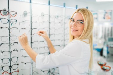Kadın optometrist gözlük optik mağazada gösterir. Gözlük seçim profesyonel gözlükçü ile bakmak