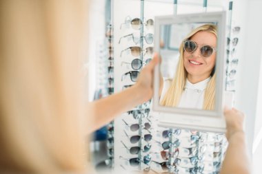 Kadın müşteri shooses güneş gözlükleri optik mağaza. Seçimi gözlük dükkanı, optometri kavramı gözleri koruma