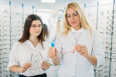 Kadın gözlükçü gözlük optik mağaza müşteri için gösterir. Gözlük seçimi ile profesyonel göz doktoru