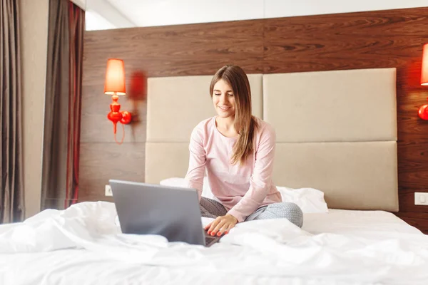 微笑的女人坐在床上 使用笔记本电脑 早上好 卧室界面的背景 — 图库照片