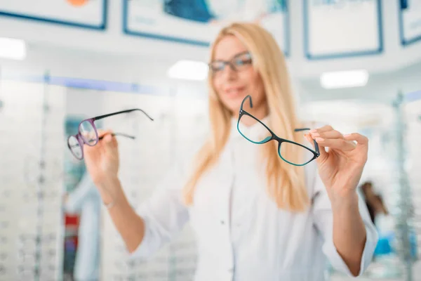 光学系の店でメガネをショーケースに立っている女性の眼鏡 プロの検眼医と眼鏡の選択 — ストック写真