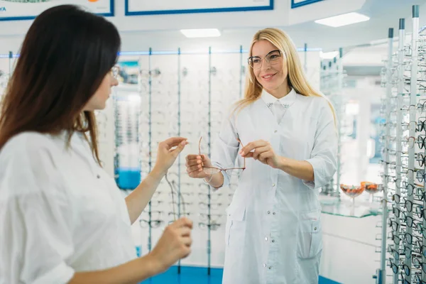女性眼镜师在光学商店向买家展示眼镜 专业视光师选择眼镜 — 图库照片