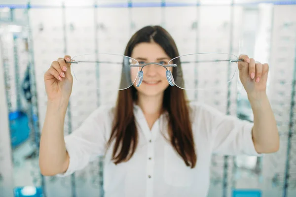 年轻女子拿着巨大的装饰眼镜 光学商店 展示与眼镜的背景 专业的眼部护理 眼镜的选择 — 图库照片