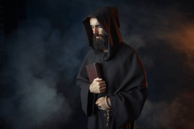 Elbise içinde ortaçağ keşiş spellbook ellerinde siyah arka plan, Gizli ritüel içinde tutar. Karanlık pelerinli gizemli rahip. Gizem ve Maneviyat