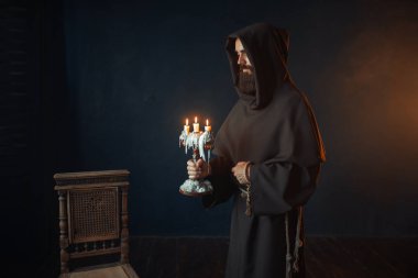 Elbise içinde ortaçağ keşiş bir şamdan ellerinde siyah arka plan, Gizli ritüel içinde tutar. Gizemli rahip mumlar ile. Gizem ve Maneviyat